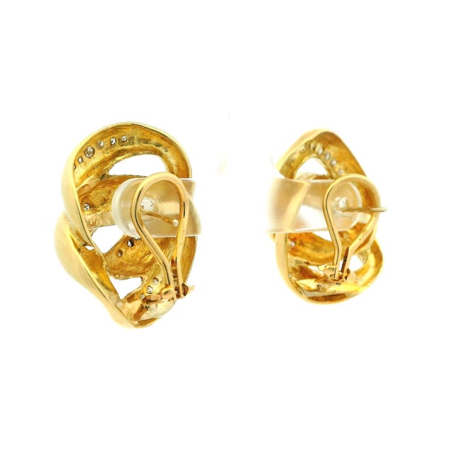 A bold and elegant pair of vintage diamond earrings crafted in 14K yellow gold, featuring a sculptural swirl design...