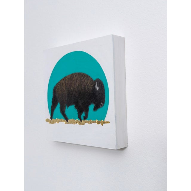 This artwork presents a solitary bison silhouetted against a vibrant turquoise circle, evoking a sense of tranquility and...