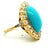 A striking antique ring crafted in 18K yellow gold, centered with a luminous 14-carat oval cabochon turquoise, surrounded...