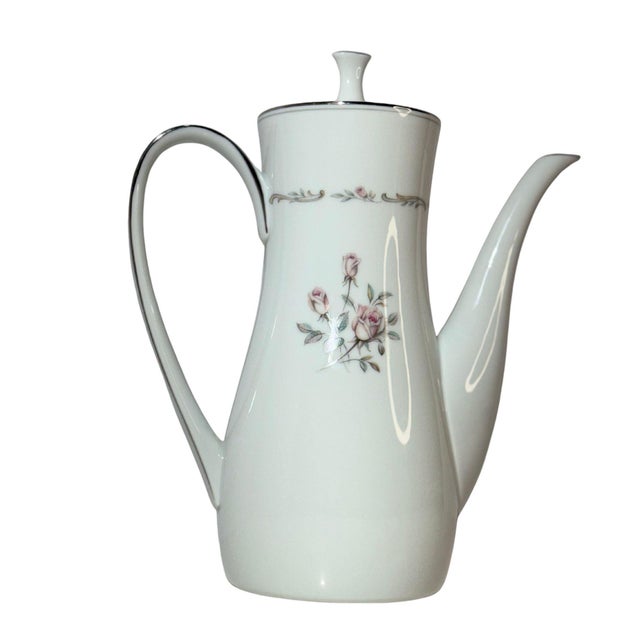 The “Mayfair” coffee pot (pattern 6107) by Noritake pairs a bright white porcelain body with pale pink roses and a...