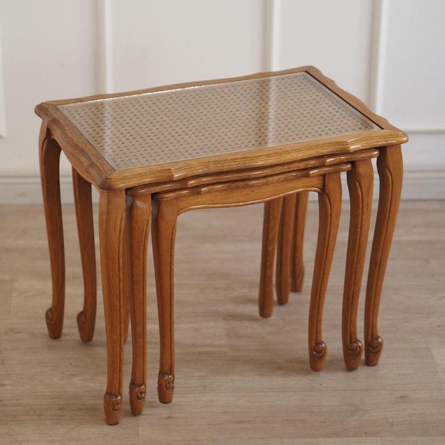 Decorative 3-piece set of stackable wooden nesting tables with glass top and fine Viennese weave. The vintage ensemble can...