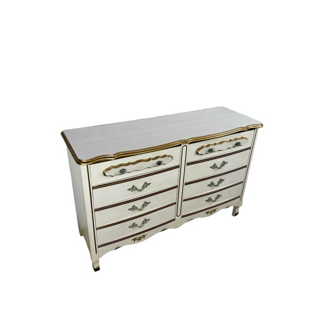 This vintage French Provincial dresser combines an elegant Louis XV-inspired silhouette with a decorative cream-and-gold...