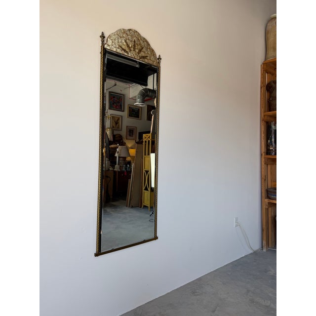 Striking Italian Hollywood Regency wall mirror featuring an elegant arched top adorned with natural shell inlay,...