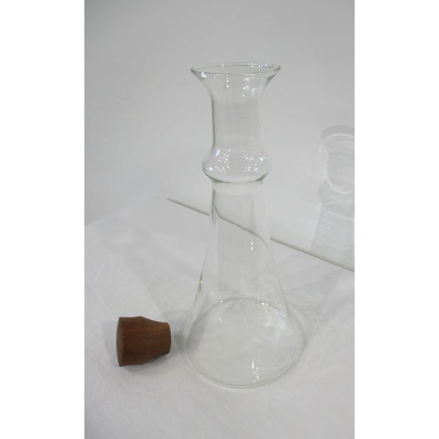 A sculptural mid-century handblown clear glass wine or liquor carafe with aesthetically pleasing turned teak wood stopper....