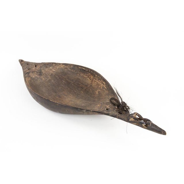 Its elongated oval shape recalls that of a canoe, it has two carved handles shaped like stylized animals. This artwork is...