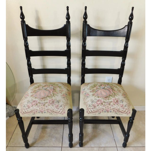 Beautiful pair of vintage black wood ladderback side chairs with courting couple tapestry seats. The chairs are all...