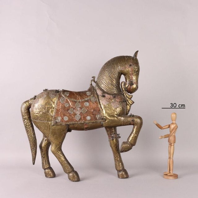Wooden horse covered in embossed and chiseled brass and copper sheet metal with applied bells, reins and chain. This piece...