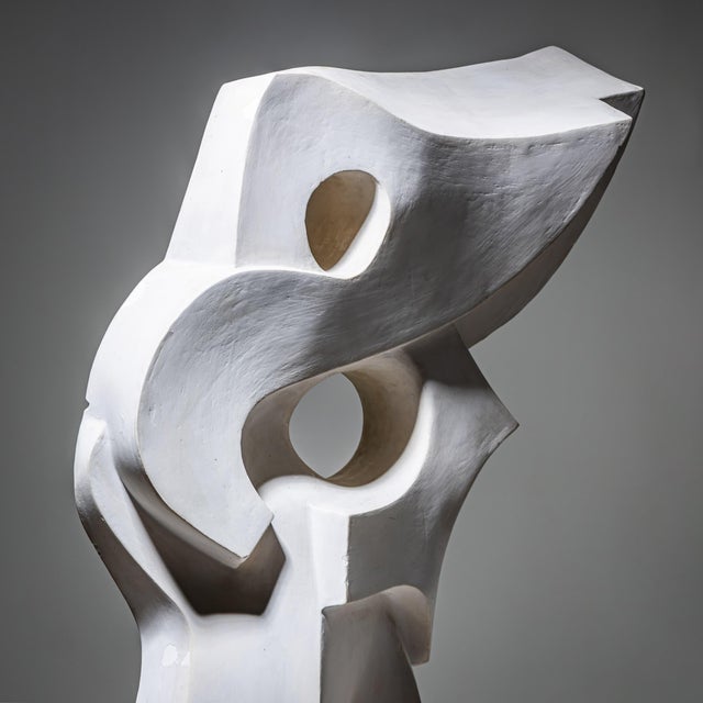 Large white ceramic sculpture of organic, asymmetrical form with dynamic flowing lines and circular piercings reminiscent...