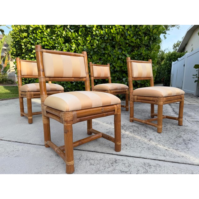 A handsome set of four vintage elephant bamboo dining chairs distinguished by their substantial bamboo frames, wrapped...