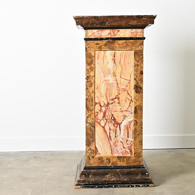 A large, 19th century Dutch square column or pedestal, covered in a variety of painted faux-marble to elevate precious...