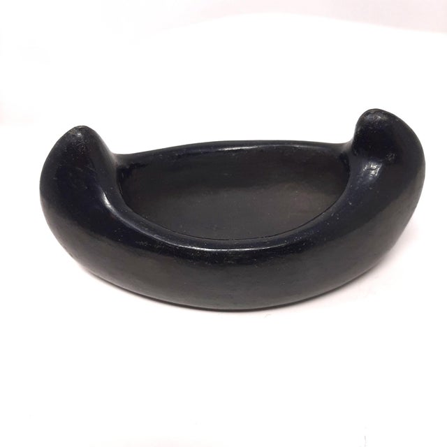 This canoe has a glossy black glaze on the outside with no markings on it. It could be used as a mortar and pestle when...