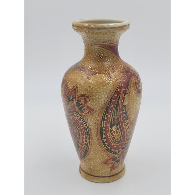This charming porcelain bud vase features a rich, textured design inspired by traditional Japanese Satsuma ware. The body...