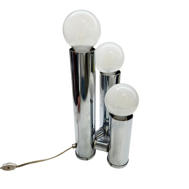 Striking vintage three-light chrome table lamp with a sculptural Space Age design. Three cylindrical chrome columns rise...