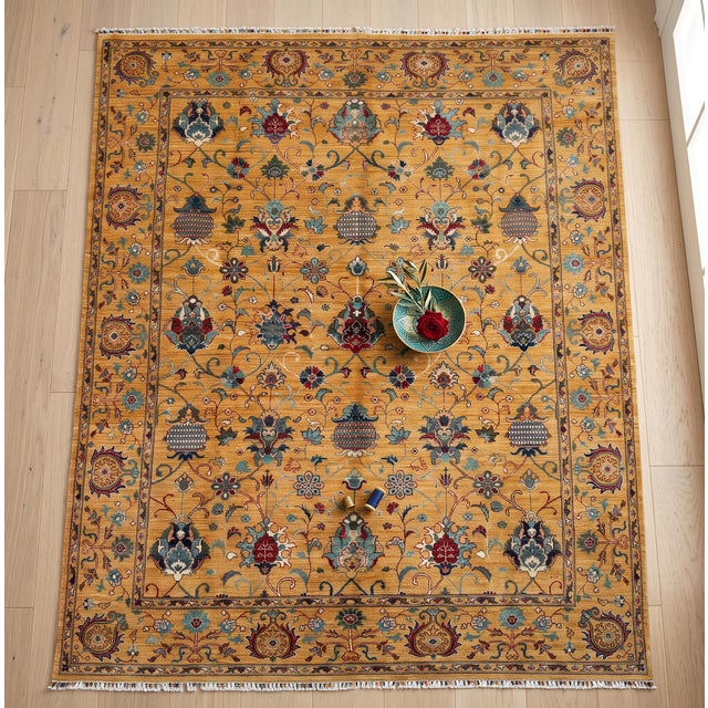 A hand-knotted area rug in the Sultanabad design, woven in Afghanistan on a warm saffron gold ground with pomegranates,...