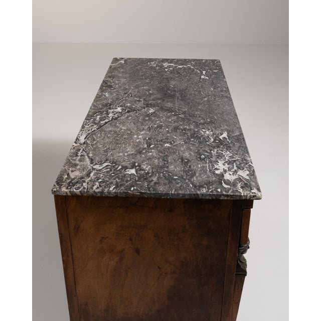A handsome French Empire chest of drawers featuring rich flame mahogany veneers with striking book-matched grain across...