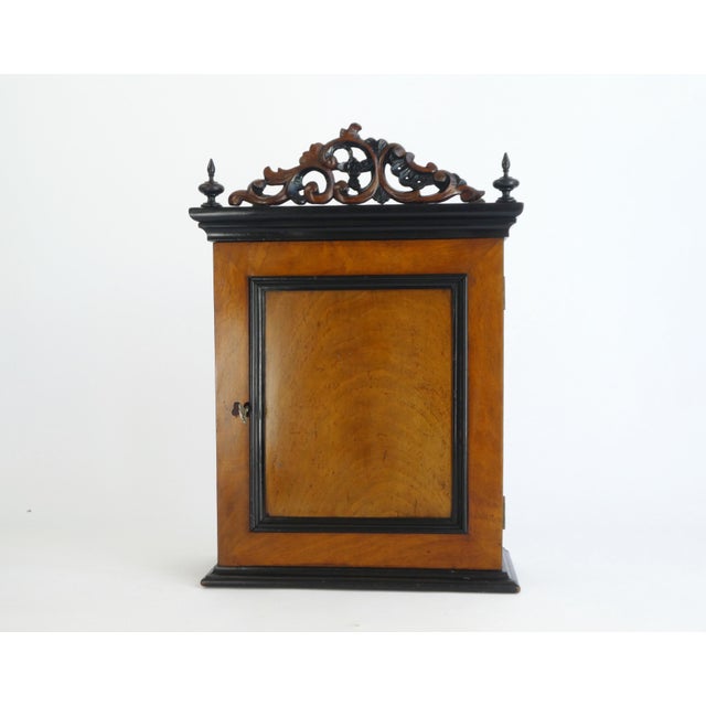 Eye catching vintage French cabinet from the 60's with a stunning hand carved ornament on the top. The brown and black...