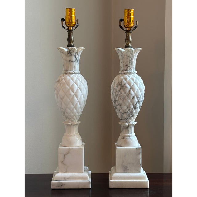 Offering a gorgeous pair of circa 1950 Italian alabaster table lamps featuring elegant hand sculpted pineapples atop a...