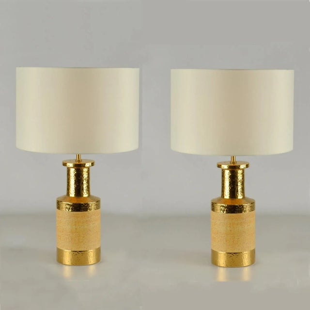 Ceramic cylinder shape table lamps where produced in stoneware with a light brown glaze. The border at the neck is gilded,...