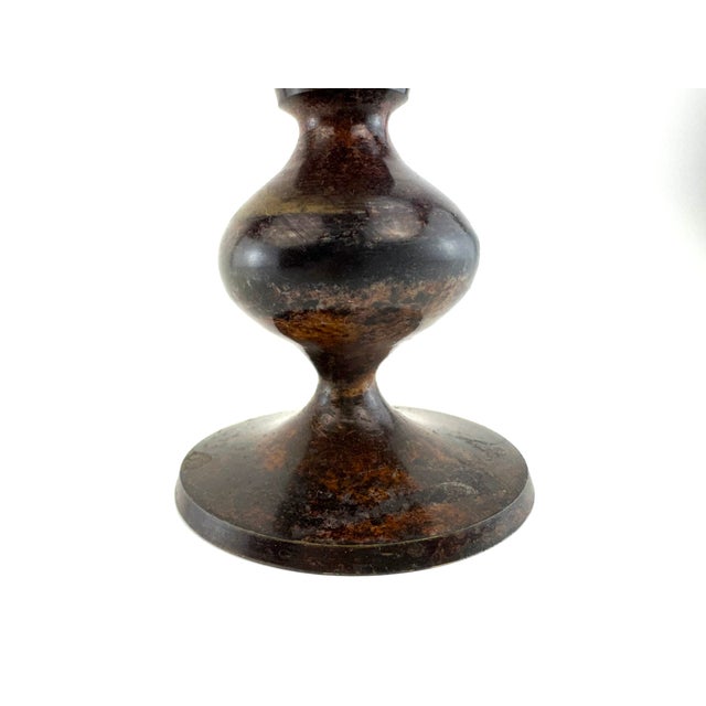 A vintage metal urn vase in a classic trophy form, featuring a richly aged, mottled patina in deep brown and black tones...