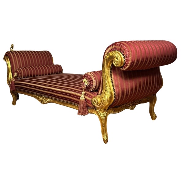 This Regency style daybed has dramatic outswept scroll arms carved with acanthus and finished in gilt, raised on carved...