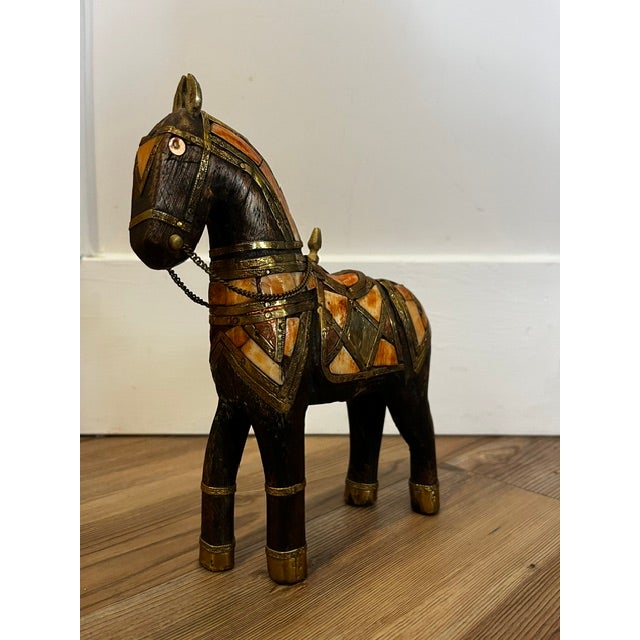 This is a vintage handcrafted wooden horse figurine originating from India.It features intricate hammered brass, copper,...