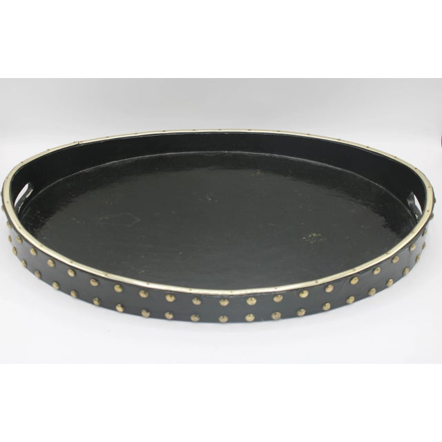 A stunning Mid Century Modern style black and gold wooden lacquered mirror with pierced handles, circa 1960s. This is a...