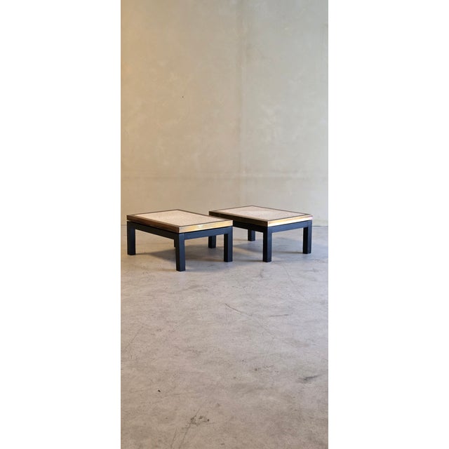 A refined pair of travertine side tables featuring solid travertine stone tops framed with elegant brass sidings. The...