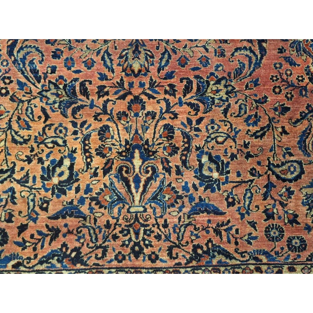The rug has a traditional Persian design, a reddish brown to terracotta dominates the background featuring an intricate...