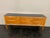 Maple chest of drawers, spindle legs with brass finials, and a blue glass top; the design is attributed to Paolo Buffa....