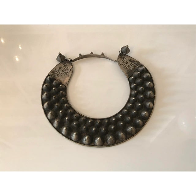 Hand made metal sculptural body adornment with 3 rows of raised cone-shaped elements in varying sizes. There are inscribed...