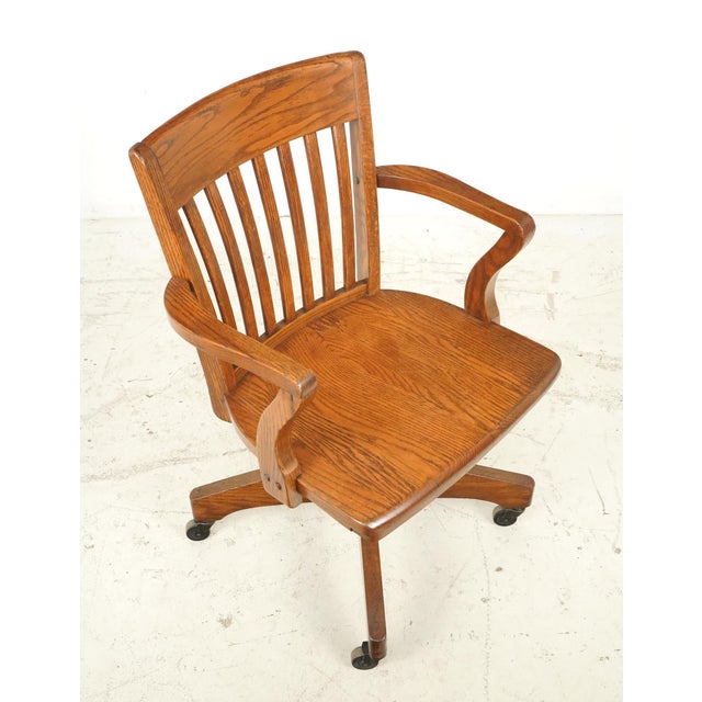 Antique swivel oak office chair, often referred to as the banker's chair, manufactured in the early 20th century. It...