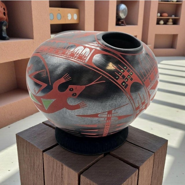 A signed Mata Ortiz pottery vessel by Cesar Bugarini, distinguished by its sculptural double-opening form and finely...