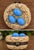 Charming hand-painted porcelain hinged trinket box designed as a bird’s nest holding three glossy blue eggs. The textured...