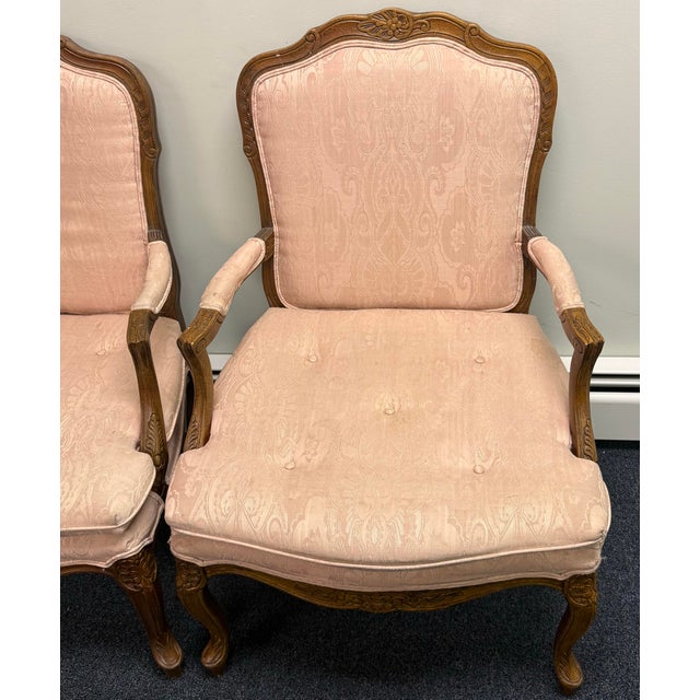 Elegant pair of French Louis XV–style carved armchairs featuring gracefully shaped walnut-toned frames with ornate floral...