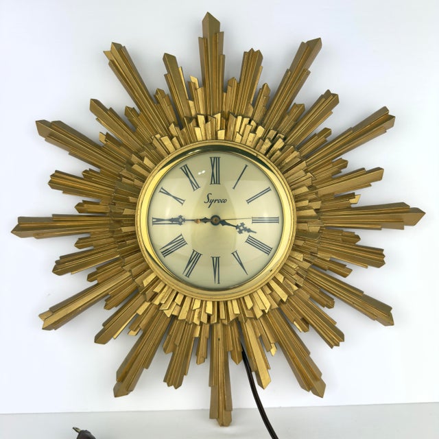 A striking vintage Syroco sunburst wall clock featuring a layered gilt finish and classic Atomic Age styling. Produced by...