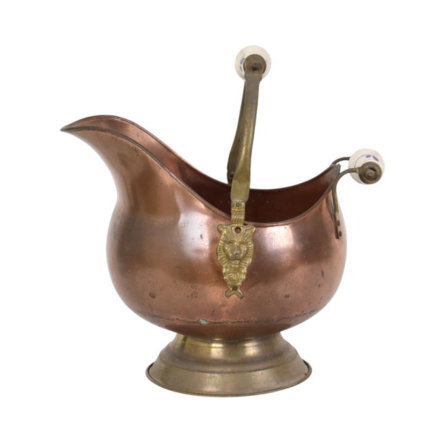 A charming, vintage helmet-shaped coal scuttle made of red copper and brass, featuring blue-and-white Delftware handles;...