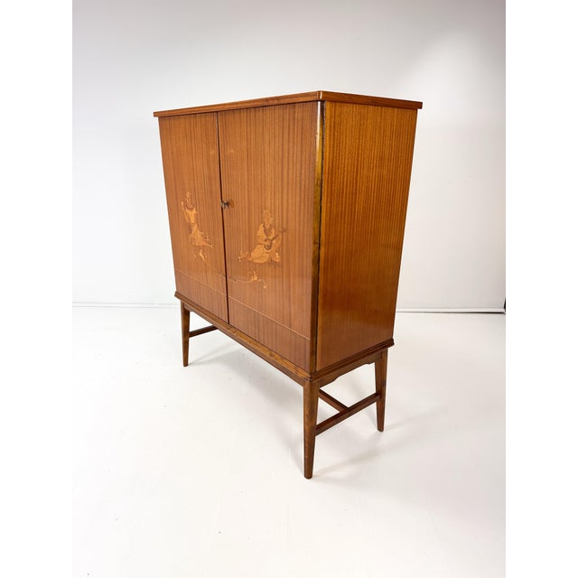 1940’s Swedish Cabinet attributed to Erik Mattson. Beautiful intarsia woodworking. Doors conceal interior shelves and...