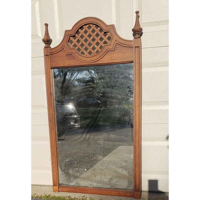 1960s Walnut mirror featuring beveled glass and carved walnut frame. Its design captures the grace of a bygone era and...