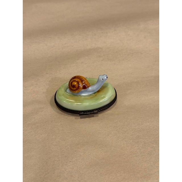 This is a porcelain limoges box. It depicts an escargot with a light detailing inside. It was curated and hand painted in...