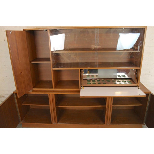 Large two piece bookcase with bottom cabinet. Glass front top cabinet with drop down bar storage. Base features two...