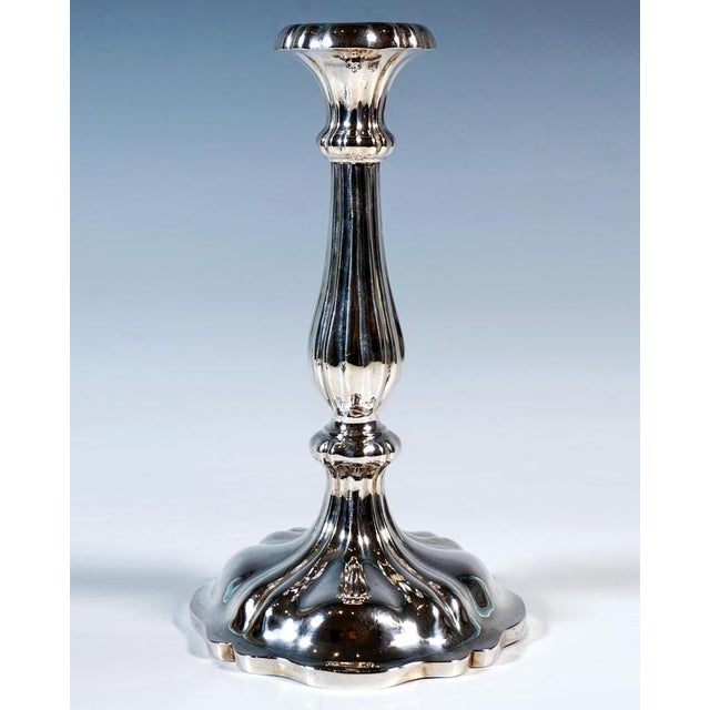 Two festive Biedermeier silver candlesticks on a four-sided, curved base with a curved edge, baluster-shaped shaft with...