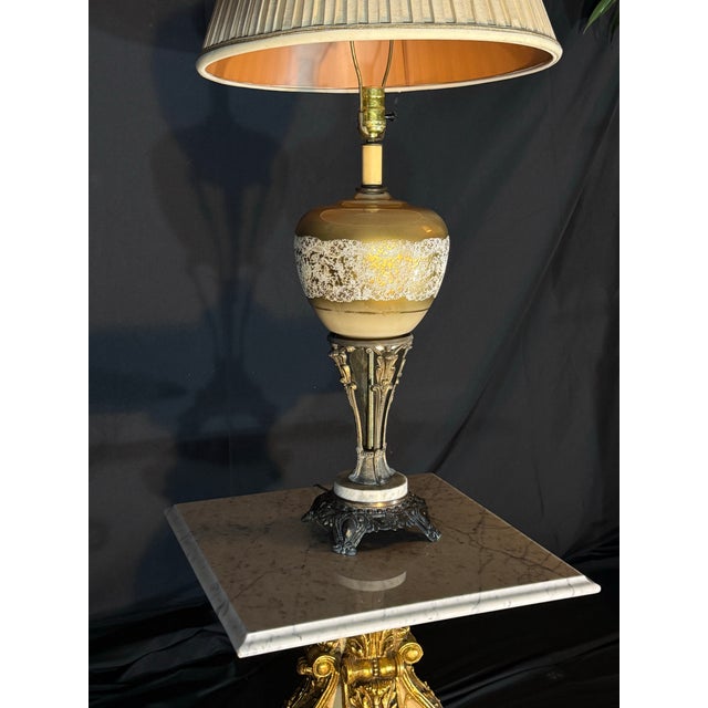 A vintage-style ornate table lamp featuring a warm gold-toned glass body, intricate decorative patterning, antique bronze-...