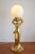 A figurative Hollywood Regency table lamp from the 1980s - The table lamp is made of ceramic and glazed with gold - The...