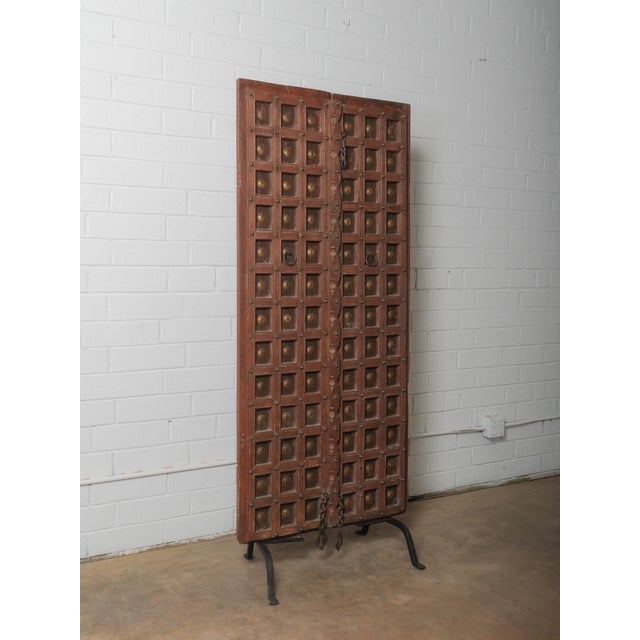 A striking architectural fragment presented as sculptural décor, this carved wooden door is mounted on a custom iron...