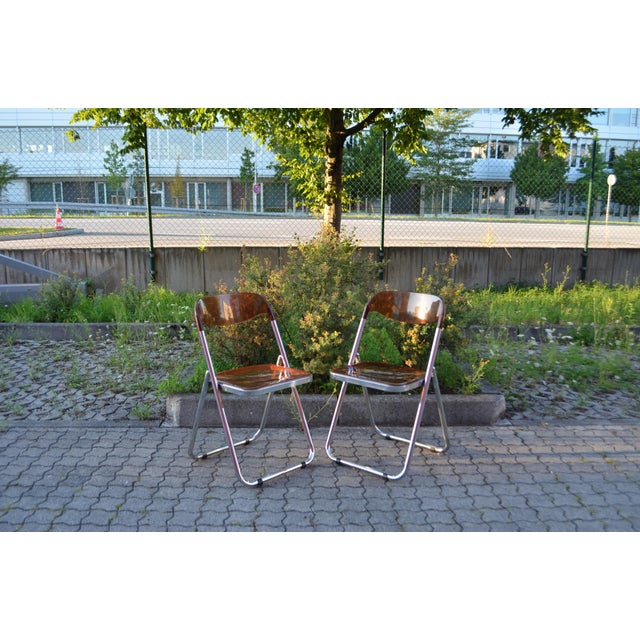 A striking pair of Italian folding chairs from the 1960s–1970s, marked “Modello Depositato.” The chairs feature a sleek...