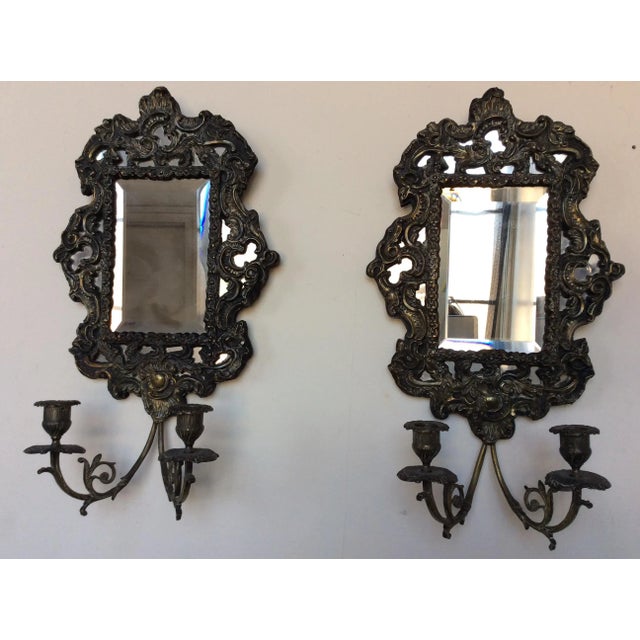 Amazing pair of antique European wall sconces each having two candle holder arms and ornate brass repousse frames. Rare to...
