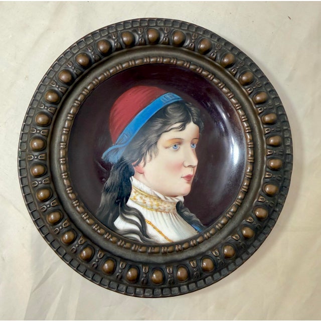 This antique collector plate from the 19th century features a beautifully painted portrait on a bronze mounted porcelain...