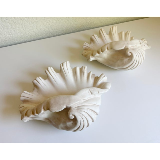 A pair of vintage plaster clam shell wall pockets designed in the signature 1930s-1940s Hollywood Regency style....