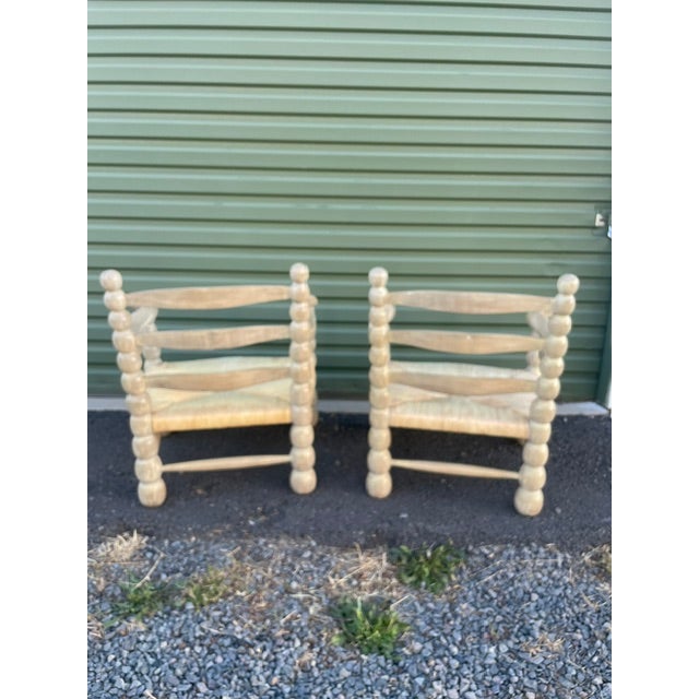 Vintage lounge chairs featuring a sculptural bobbin-style carved wood frame finished in a distressed, crackled patina that...