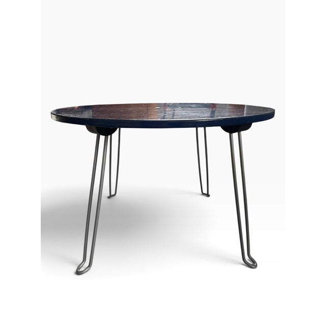 Vintage round occasional/side table featuring a striking deep blue laminate top and sculptural folding hairpin-style metal...